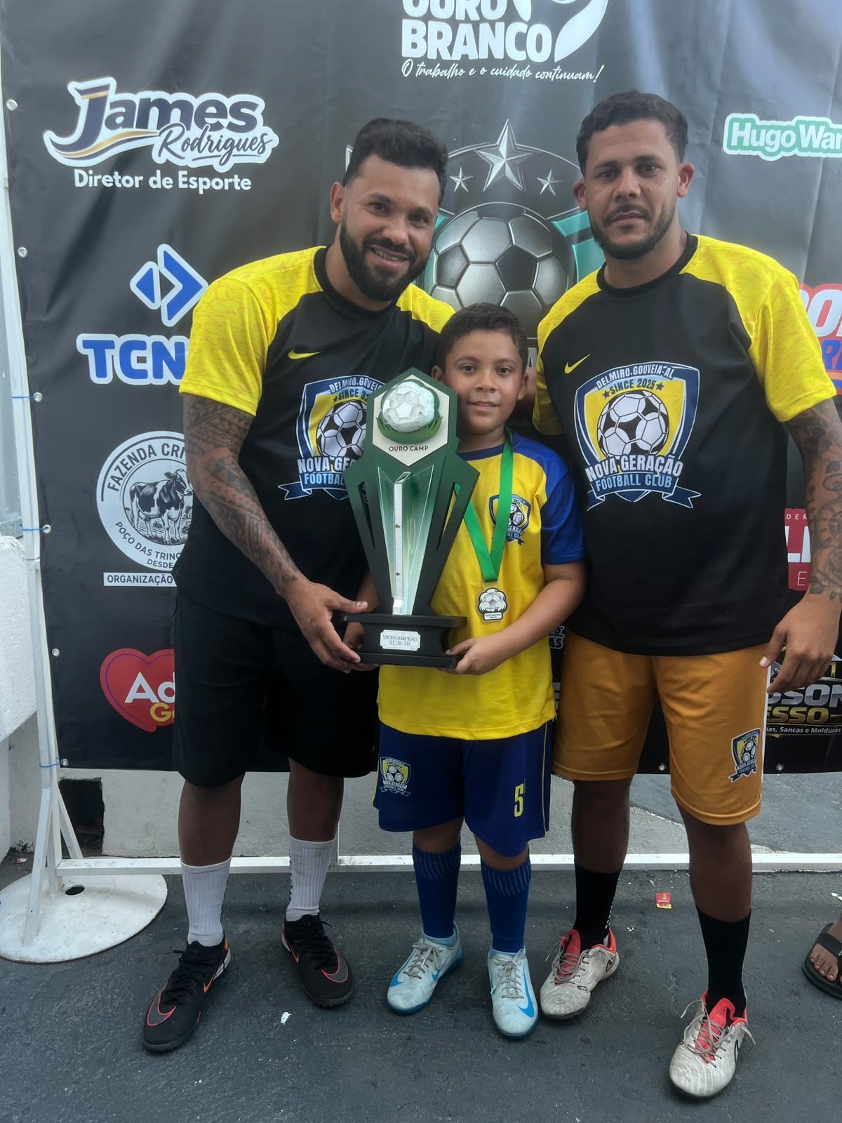 Atleta e professores exibindo o troféu de vice-campeão Sub-10